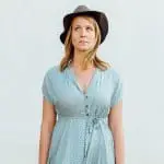 woman in her 40s with a blue dress and a grey hat