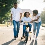 mom and dad teaching their little girl to ride a bike