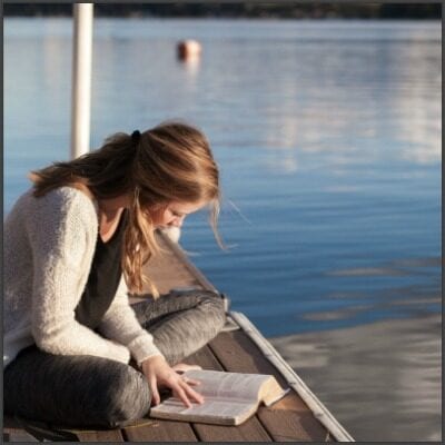 girl with a bible on a dock